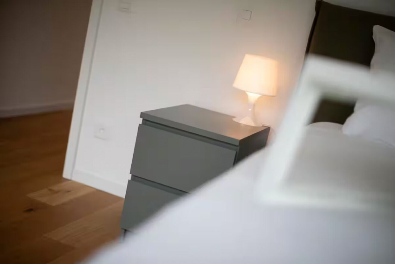 Ein Schlafzimmer mit Nachttisch, Lampe und Bett.