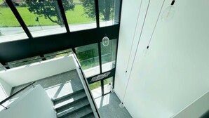 A modern staircase with glass railings and a view of a green outdoor area. - An oasis of peace in nature (PPegasus 11 Residenza Ticino) (Bellinzona)