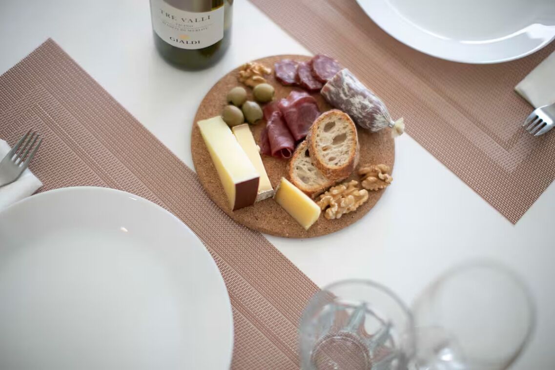 Una mesa dispuesta con una tabla de quesos, una botella de vino y platos.