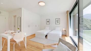 Ein modernes, minimalistisches Schlafzimmer mit Bett, Nachttischen und einem großen Fenster mit Blick ins Freie.