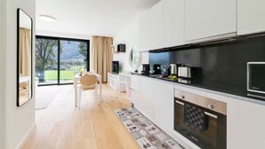 A modern kitchen with white cabinets, a black countertop, and a built-in oven. - An oasis of peace in nature (Sirio 09 Residenza Ticino) (Bellinzona)