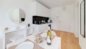 A modern, minimalist living space with a dining area, a kitchen, and a large mirror. - An oasis of peace in nature (Sirio 09 Residenza Ticino) (Bellinzona)