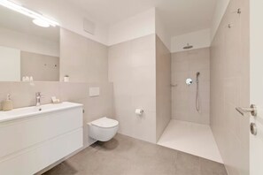A modern bathroom with a white vanity, toilet, and shower area. - An oasis of peace in nature (Hydra 06 Residenza Ticino) (Bellinzona)