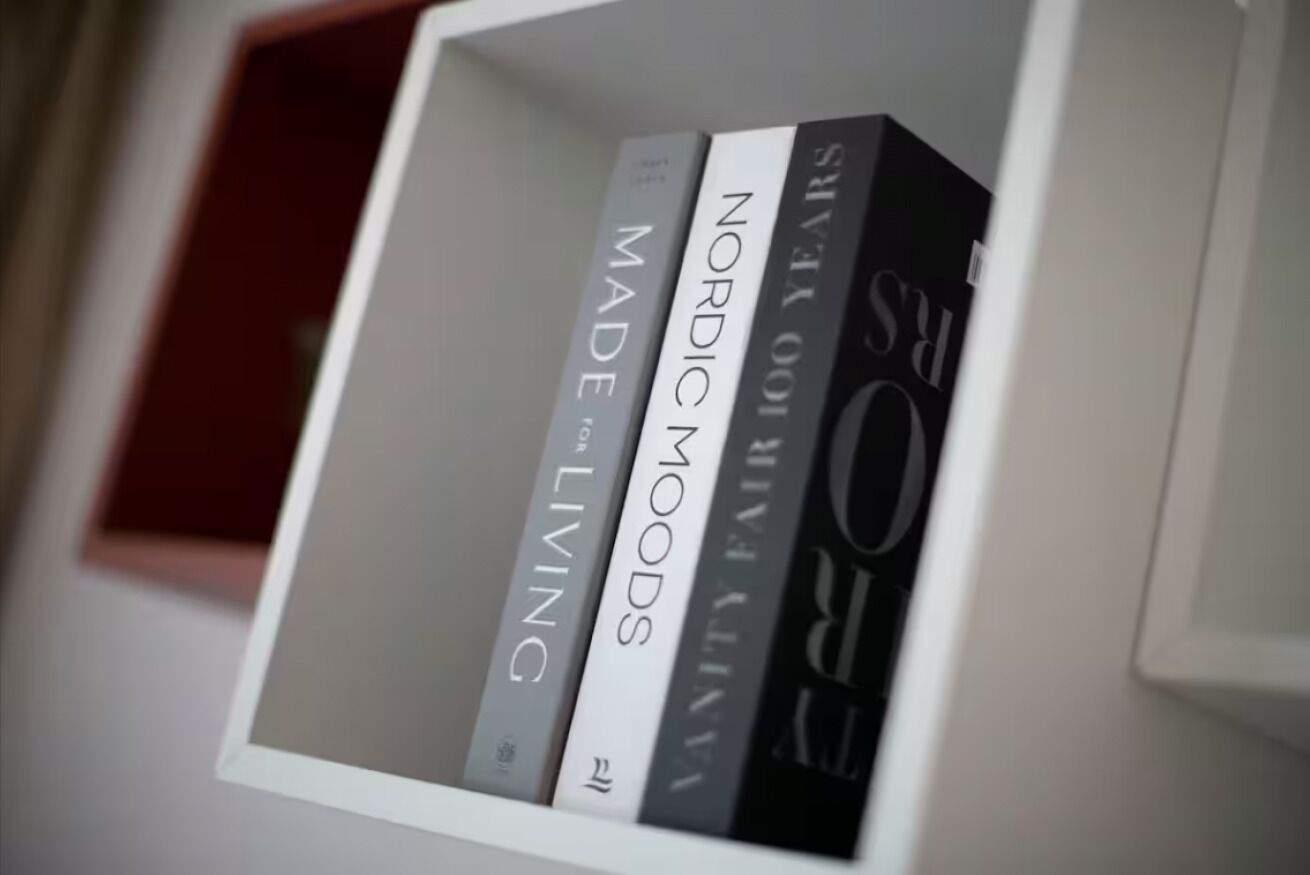 Une bibliothèque contenant des livres intitulés « Made Living », « Nordic Moods » et « Vanity Fair ».