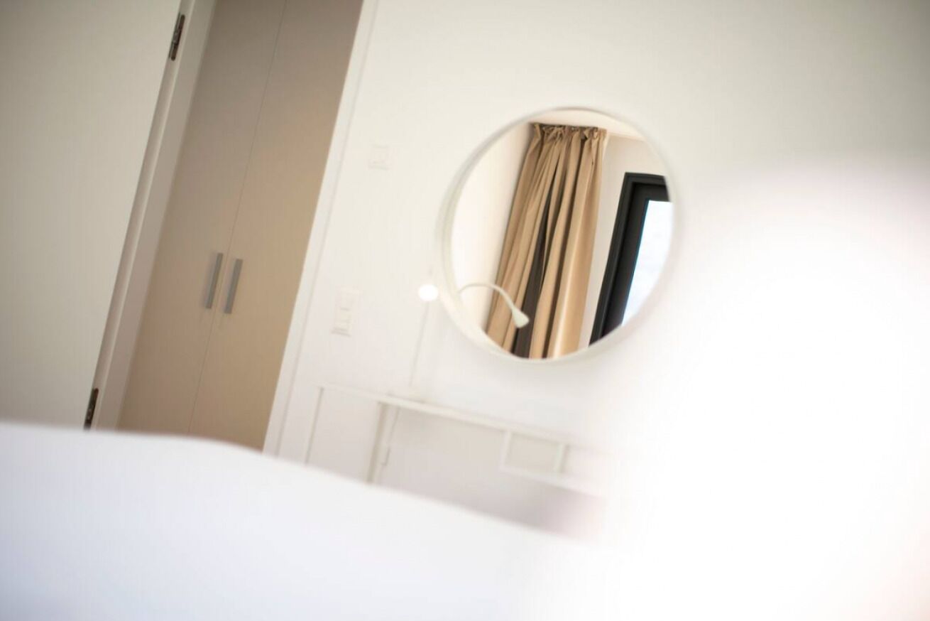 A bedroom with a round mirror, a bed, and a wardrobe.