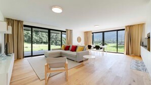 A spacious living room with a large window, a sofa, a coffee table, and a TV. - An oasis of peace in nature (Talitha 05 Residenza Ticino) (Bellinzona)