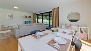 A modern dining area with a table set for two, a sofa, and a large window with curtains. - An oasis of peace in nature (Talitha 05 Residenza Ticino) (Bellinzona)