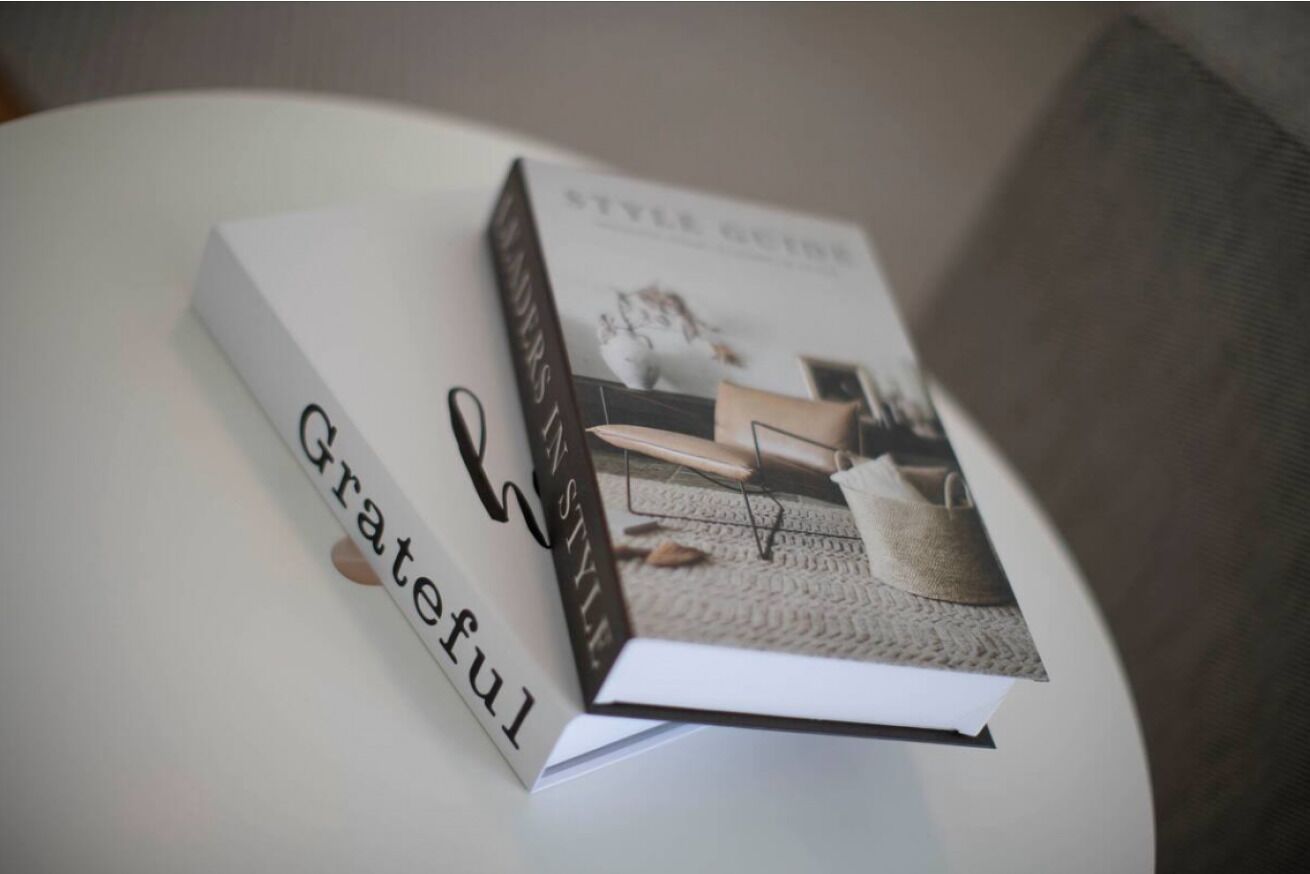 A book titled 'Style Guide' with a cover image of a person in a white outfit and a brown bag, placed on a white surface.