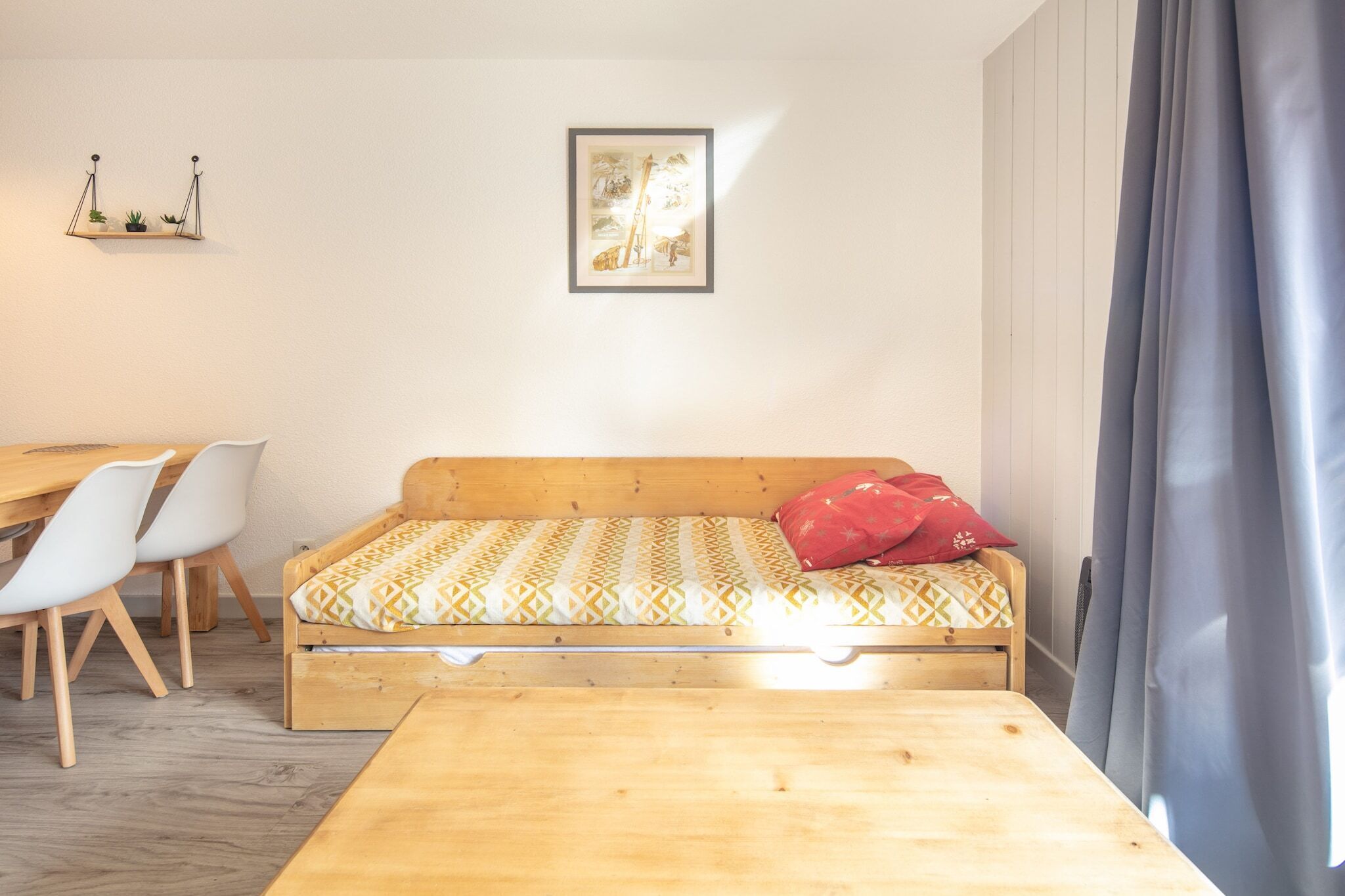 Een kamer met een houten bed, een klein bureau, witte stoelen en een lijst met een afbeelding aan de muur.