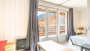 Ein Zimmer mit einem Bett, einem Tisch und einem fensterbepflanzten Fenster.