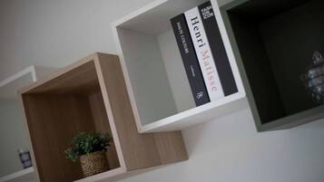 A modern, minimalist bookshelf with two books and a small plant.