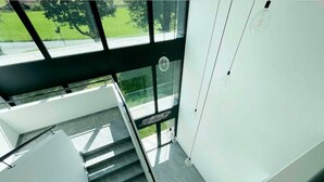 Eine moderne Treppe mit Glastrennläufern und Blick auf eine grüne Außenanlage.