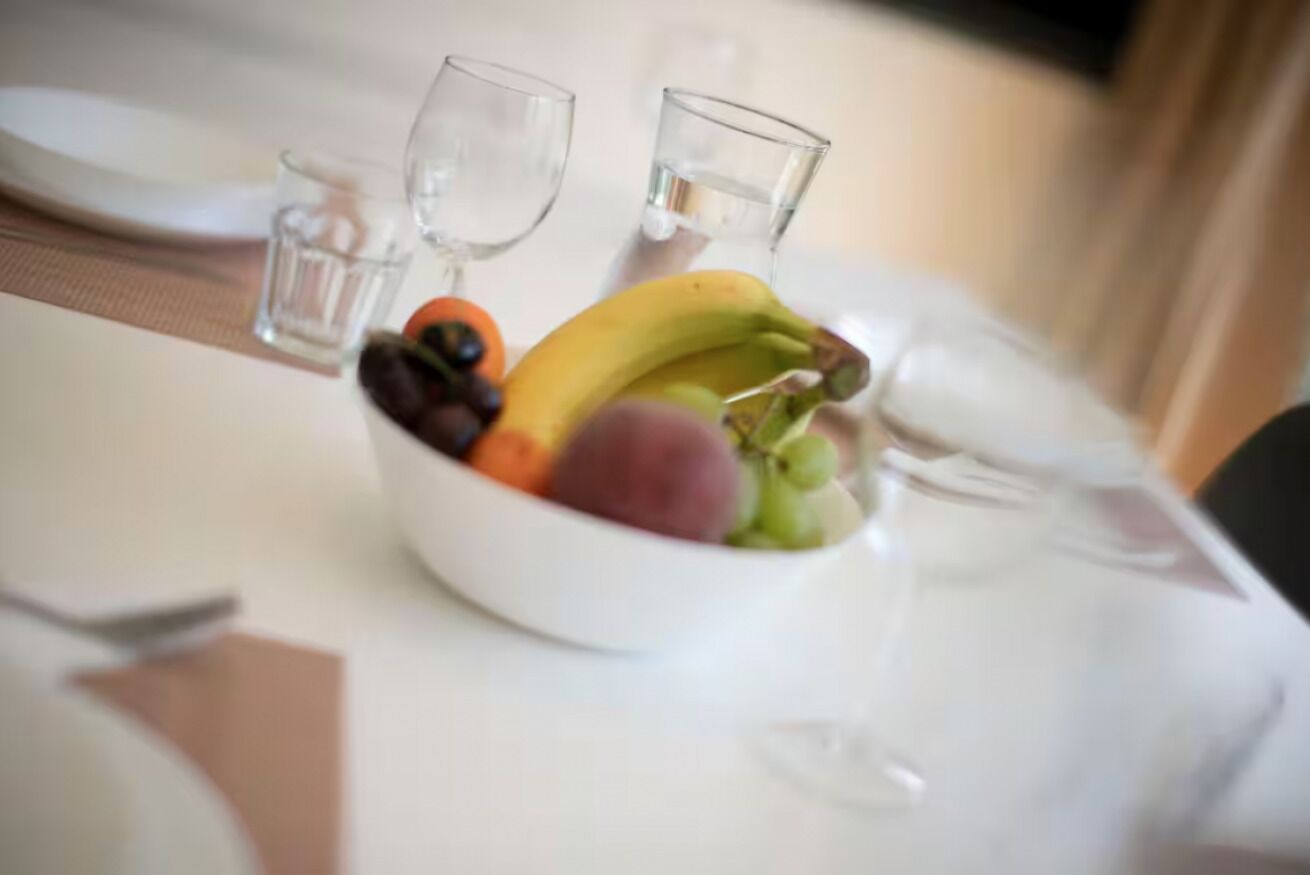 Ein Esstisch mit Obstschale, zwei Gläsern und einem Teller.