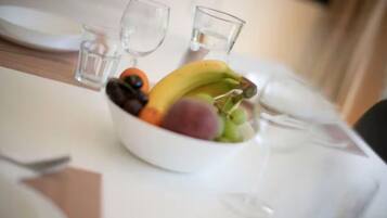 Ein Esstisch mit Obstschale, zwei Gläsern und einem Teller.