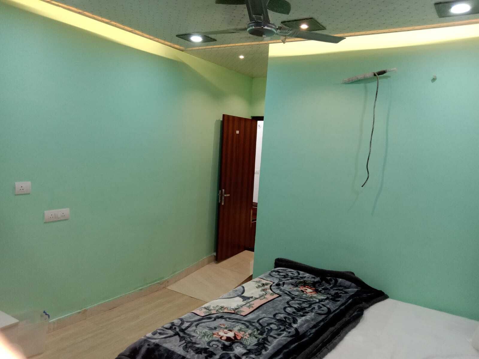 A bedroom with a bed, a ceiling fan, and a door leading to another room.