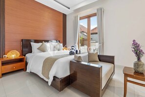 A modern bedroom with a bed, bedside table, and a small seating area. - Amaya Villa by Kozystay - Canggu (Canggu)