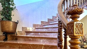 Un escalier en marbre, avec une balustrade en bois et un pot en laiton sur le côté gauche.