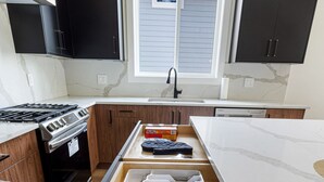 A kitchen with a built-in oven, a stove, and a window above the sink.