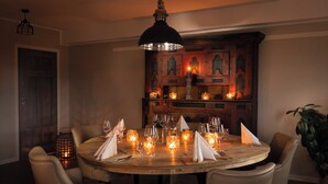 A round dining table with candles, glasses, and napkins set for a meal.