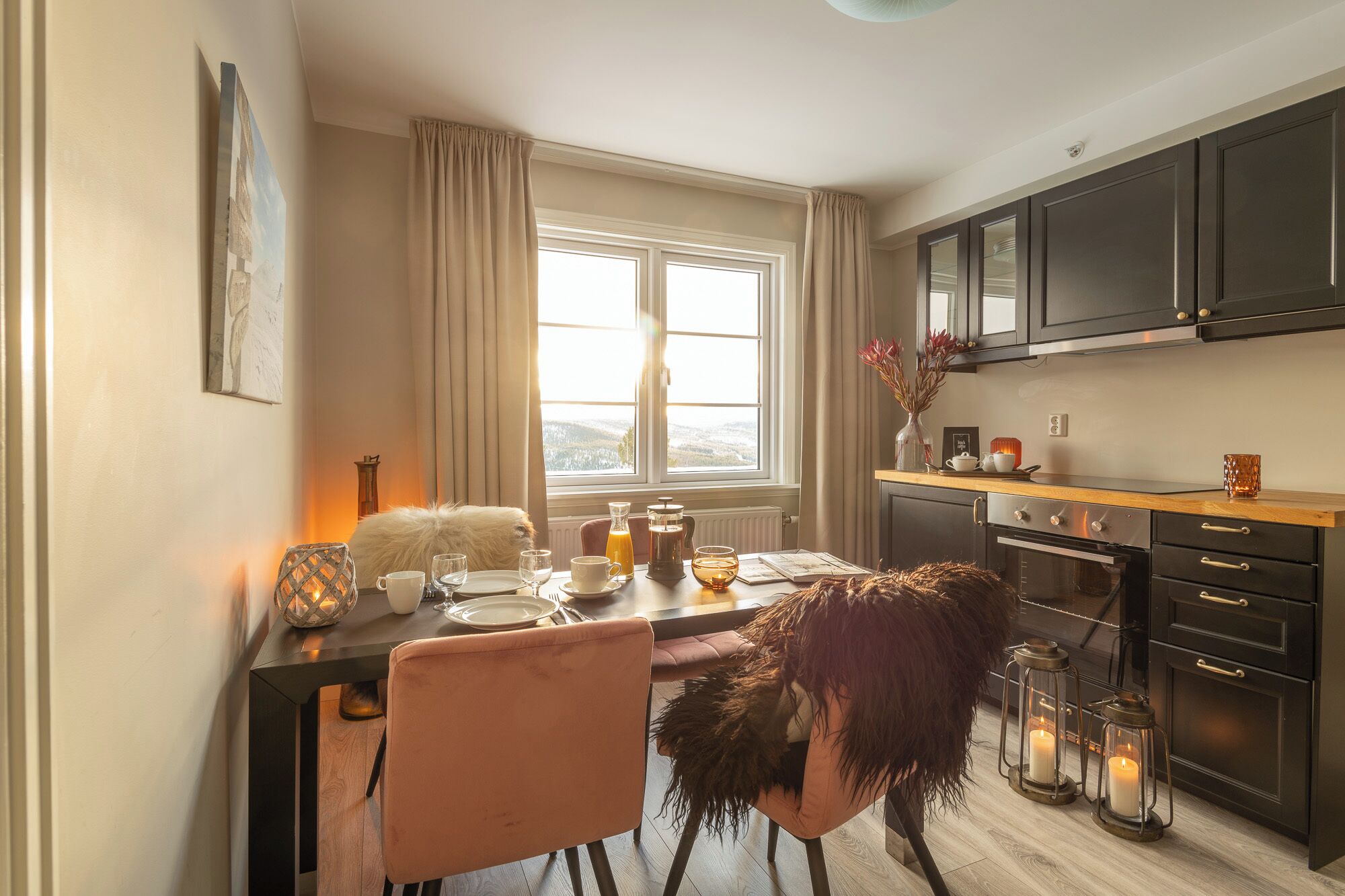 Una cocina acogedora con una mesa de comedor lista para cuatro, un ventanal con vistas y armarios oscuros.