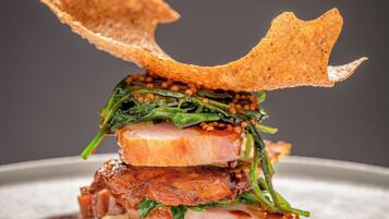 A dish with various food items including meat, greens, and a crispy element on a plate.