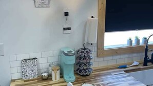 A kitchen with a wooden countertop, a coffee machine, a spice rack, and a hanging light fixture. - Mountain Top Tiny House by Beyond Expectations: 1BR w/ Mountain Views (Sevierville)