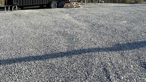 A small, black, metal RV with a window and a door, parked on gravel with trees and mountains in the background. - Mountain Top Tiny House by Beyond Expectations: 1BR w/ Mountain Views (Sevierville)