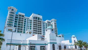 Um hotel grande, de vários andares, com design arquitetônico moderno, destacando-se por uma torre imponente e várias varandas.