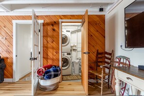Une buanderie équipée d’un lave-linge, d’un étendoir et d’une chaise.