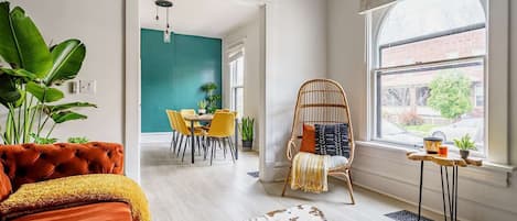 Una sala de estar moderna con comedor, un amplio ventanal y una pared de acento verde llamativa.