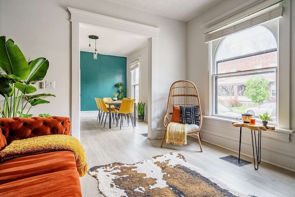 Una sala de estar moderna con comedor, un amplio ventanal y una pared de acento verde llamativa.