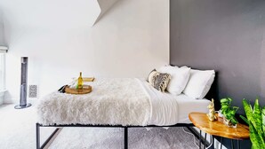 Ein modernes Schlafzimmer mit Bett, Nachttisch und einer kleinen Pflanze.