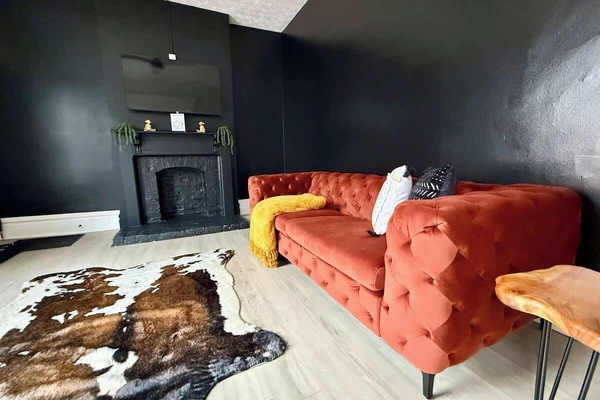 Unwind in style in our modern Jungle House living room in Columbus! Our vibrant orange tufted sofa, cozy yellow throw blanket, and chic cowhide rug create the perfect space to relax. & Our plants are looking forward to hosting you soon