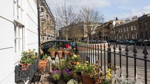 Een balkon met potplanten en een auto op de straat.