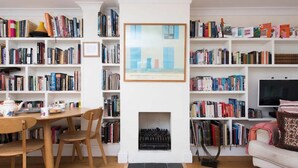 Een gezellige woonkamer met een open haard, een televisie en een boekenkast vol boeken.