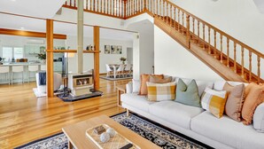 Ein geräumiges Wohnzimmer mit einer Holztreppe, einem Kamin und einem Essbereich im Hintergrund.