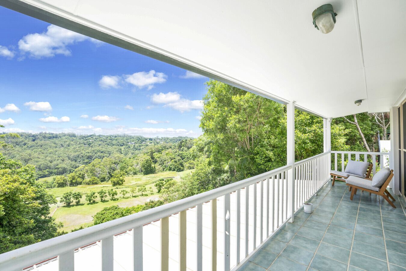 Ein Balkon mit Blick auf eine grüne Landschaft und einem weißen Geländer.