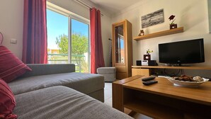 A living room with a grey sofa, a wooden coffee table, a TV, and a small table with a bowl and remote controls. - Apartment Josefa Summ (Vale de Parra)