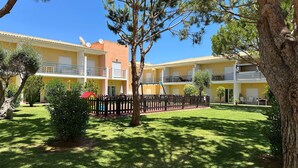A multi-story building with balconies, a fenced courtyard, and a small play area. - Apartment Josefa Summ (Vale de Parra)