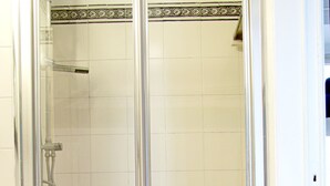 Une cabine de douche fermée par des parois en verre, dotée d’un sol carrelé et d’une bordure décorative.