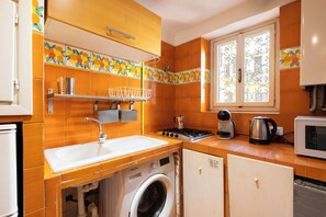A compact kitchen with a washing machine, a stove, a kettle, and a microwave. - Vacation Home Two Steps from the Vatican - Comfort and Metro Ottaviano Under House (Roma)