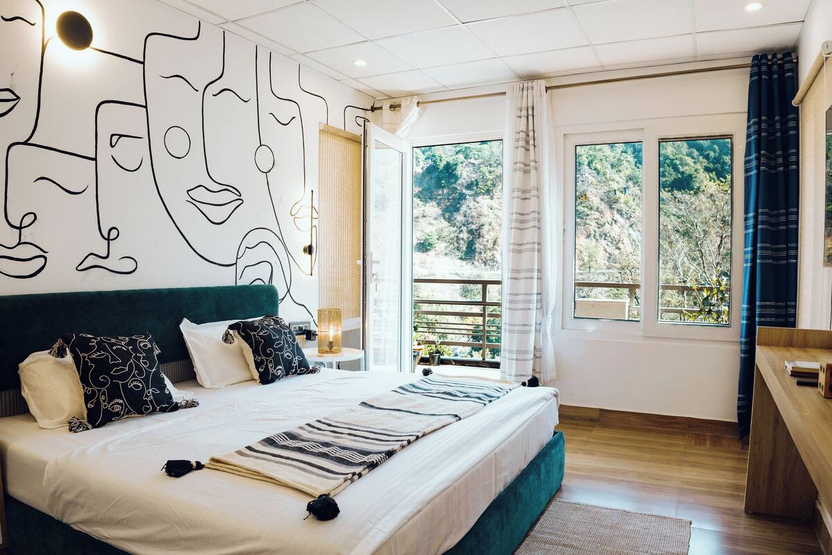 A modern bedroom with a large bed, a view of the outdoors, and a unique wall art design.