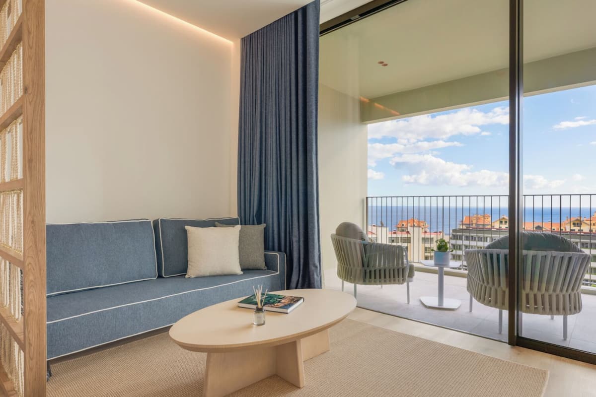 Ein modernes Wohnzimmer mit einer Couch, einem Couchtisch und einem Balkon mit Meerblick.
