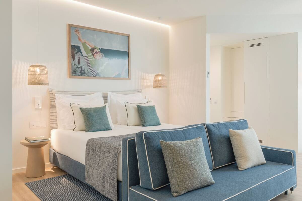 Ein modernes Hotelzimmer mit Bett, Sofa und einem Bild an der Wand.