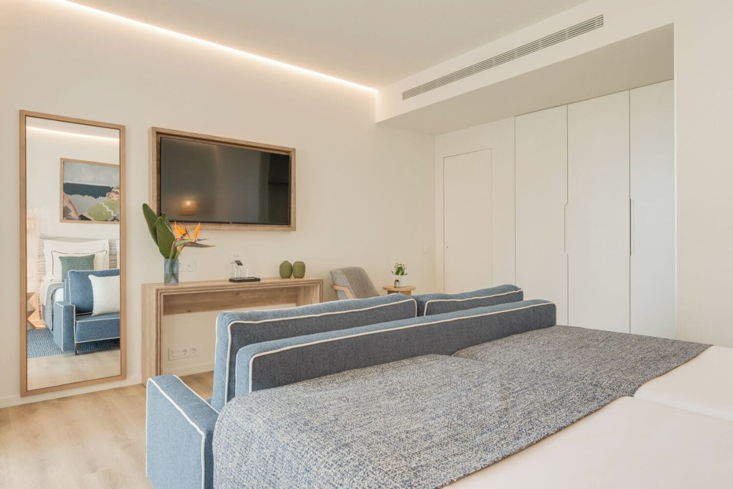 Une chambre à coucher moderne avec un grand lit, un bureau, une chaise, un miroir et une armoire.