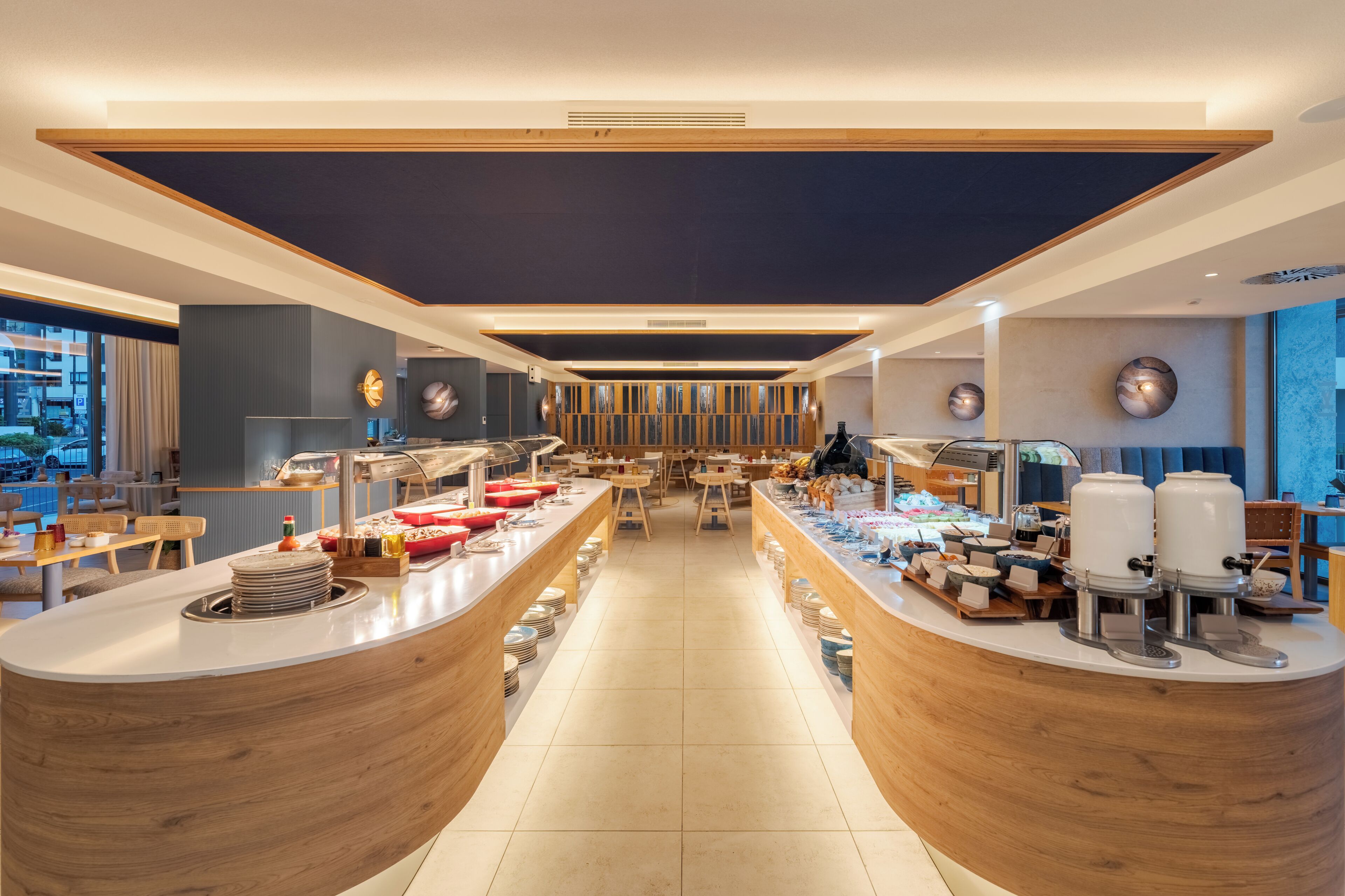 Un restaurant moderne doté d’un bar central, de plusieurs espaces de restauration et offrant une vue sur le paysage urbain.