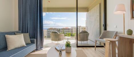 A modern living room with a sofa, two armchairs, a coffee table, and a balcony with a view of buildings.
