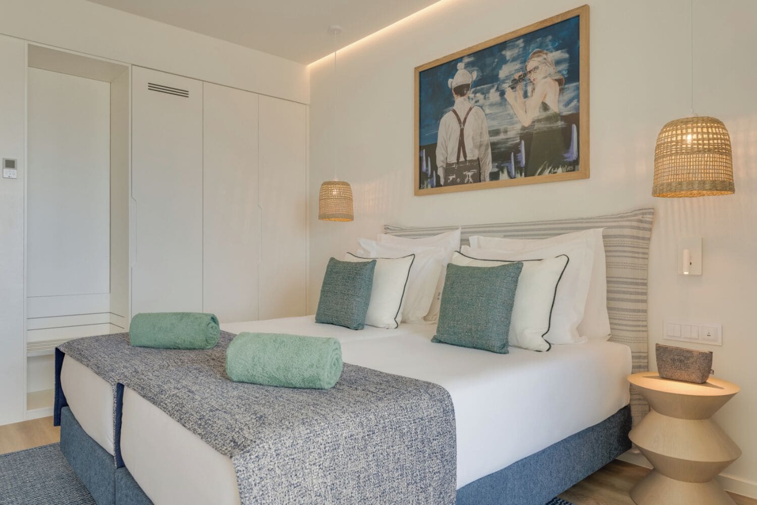 Ein modernes Schlafzimmer mit einem großen Bett, einem Gemälde darüber und einer außergewöhnlichen Nachttischlampe.