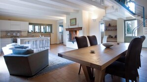 Un'ampia cucina con zona pranzo, camino e una scala che conduce a un piano superiore.
