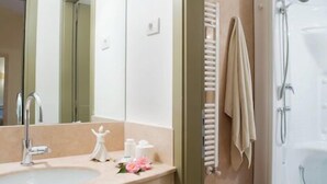 Un bagno con lavandino, specchio, porta asciugamani e doccia.